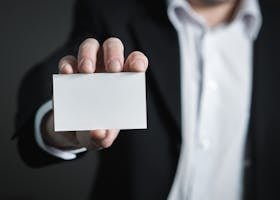 A man in a suit presenting a blank business card for corporate usage.
